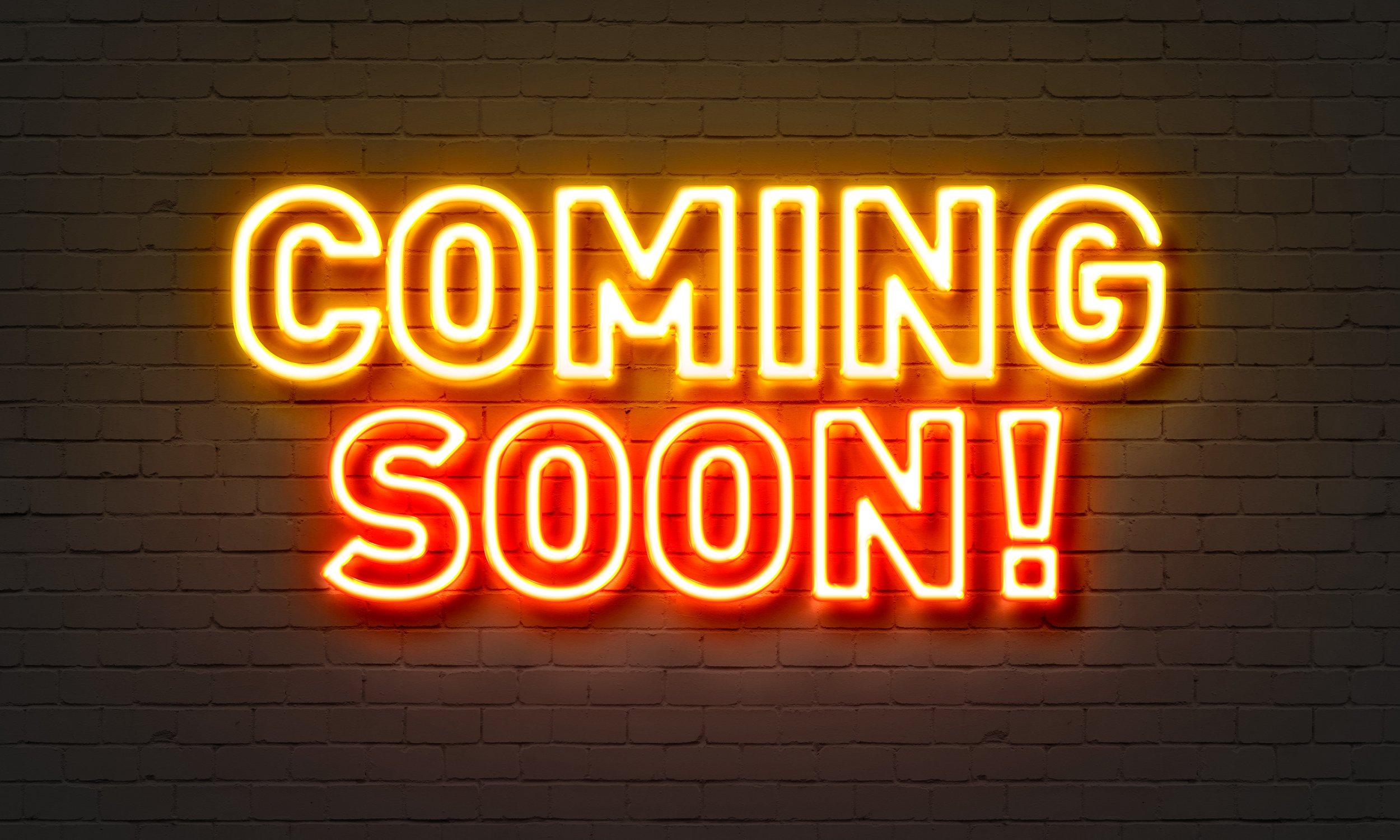 Coming soon neon sign on brick wall background
